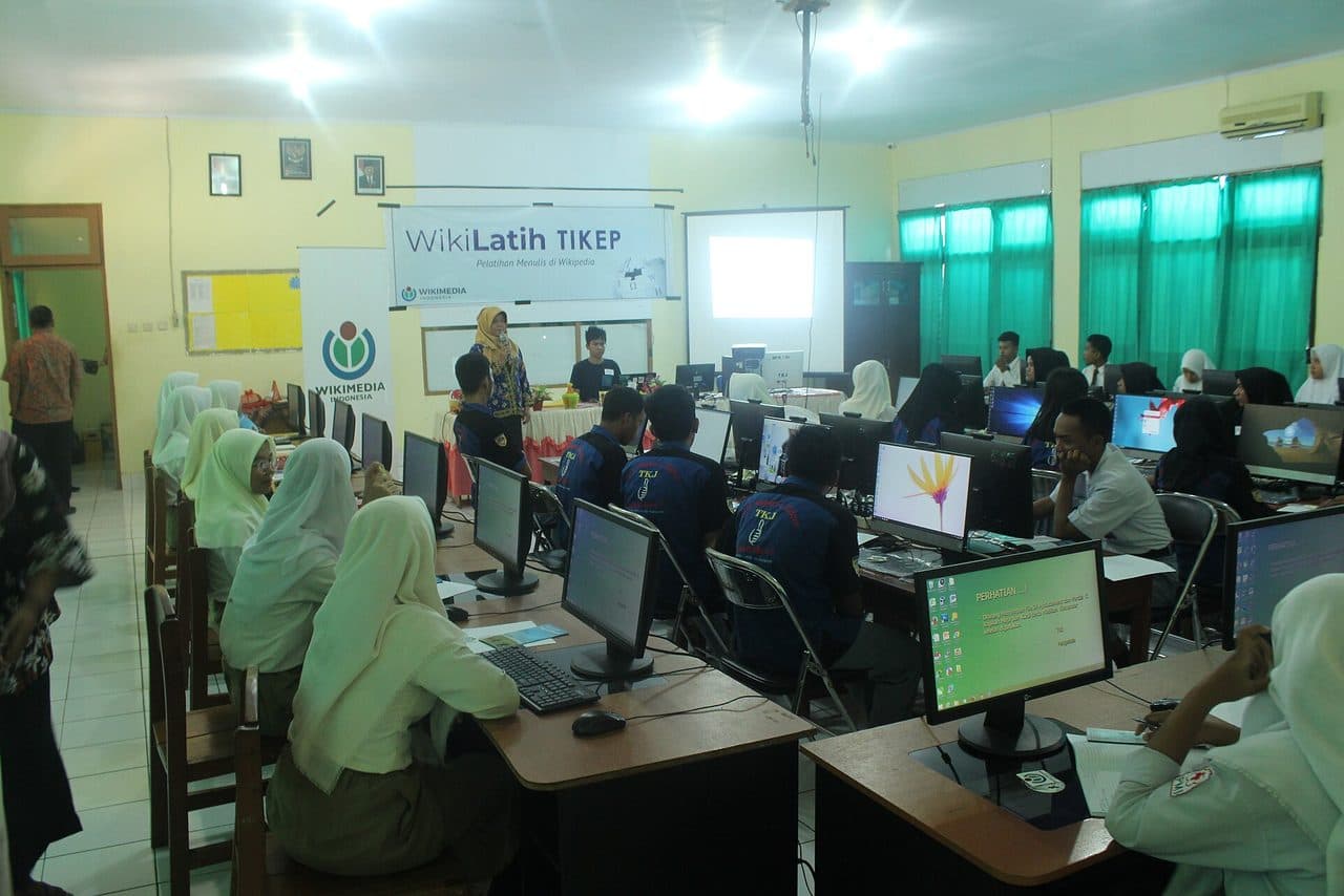 Siswa SMK bekerja di laboratorium komputer sekolah dengan layar monitor menyala di setiap meja