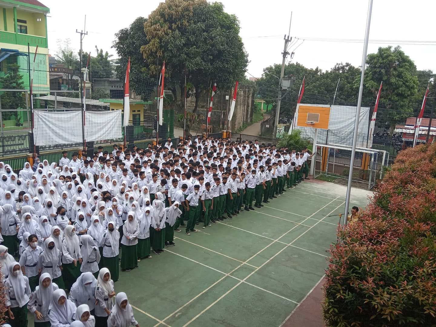 Ratusan siswa berseragam putih-hijau berbaris rapi mengikuti upacara bendera di halaman sekolah menengah di Indonesia